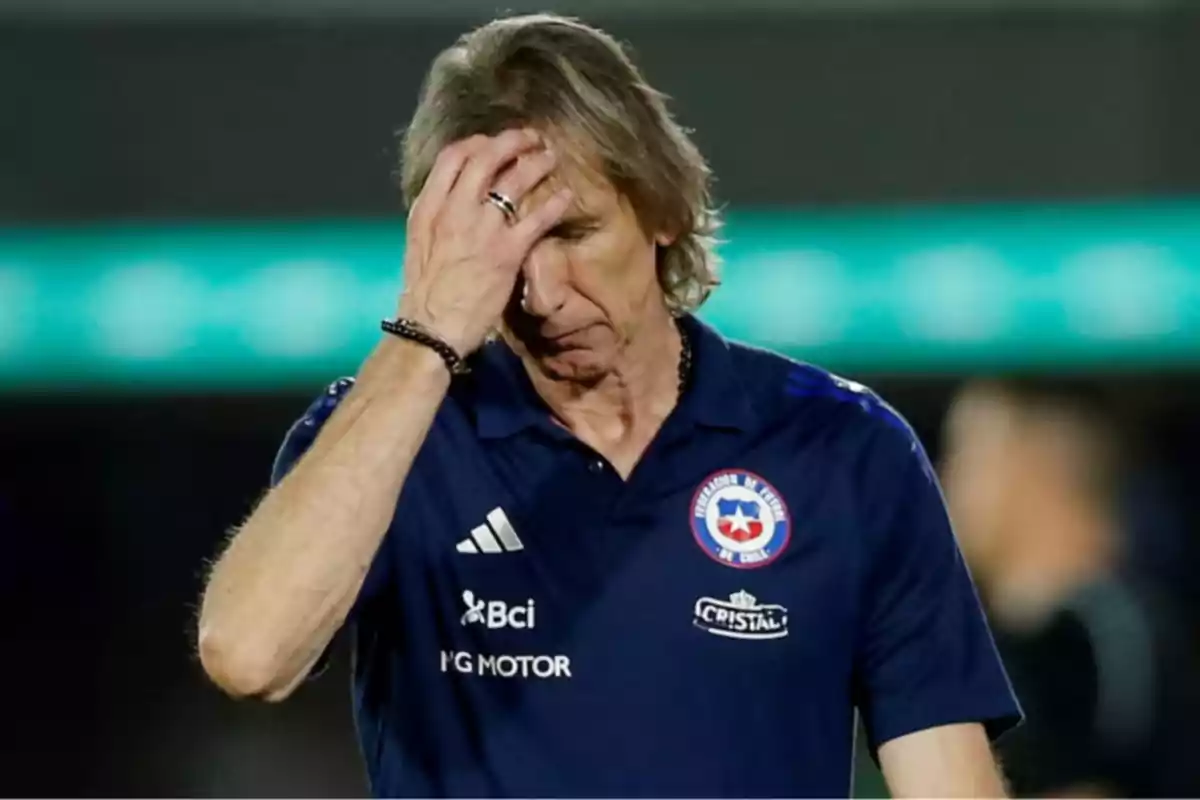 Entrenador de fútbol con gesto de preocupación llevándose la mano a la cabeza durante un partido