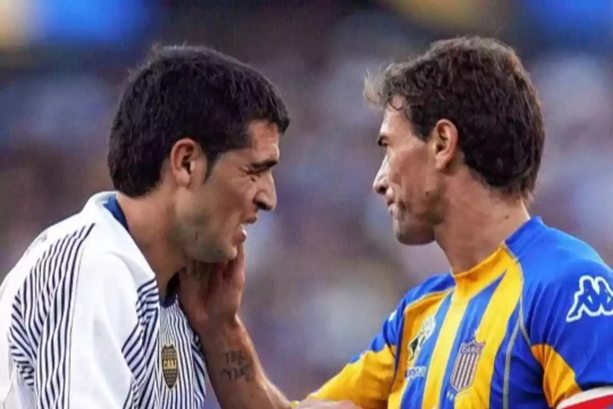 Two players look closely at each other on the field, one wearing a white and blue jersey and the other wearing a yellow and blue jersey. Two players look closely at each other on the field, one wearing a white and blue jersey and the other wearing a yellow and blue jersey.