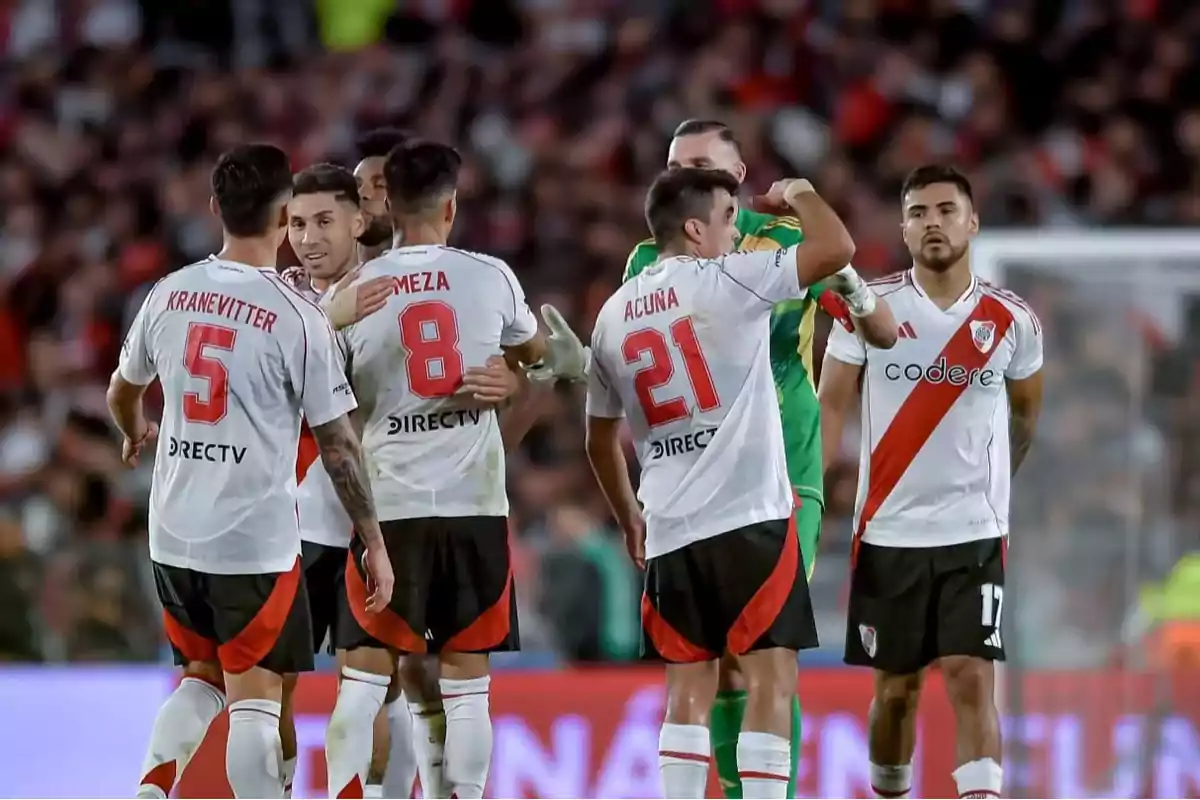 Soccer players in white and red uniforms celebrate on the field during a match.