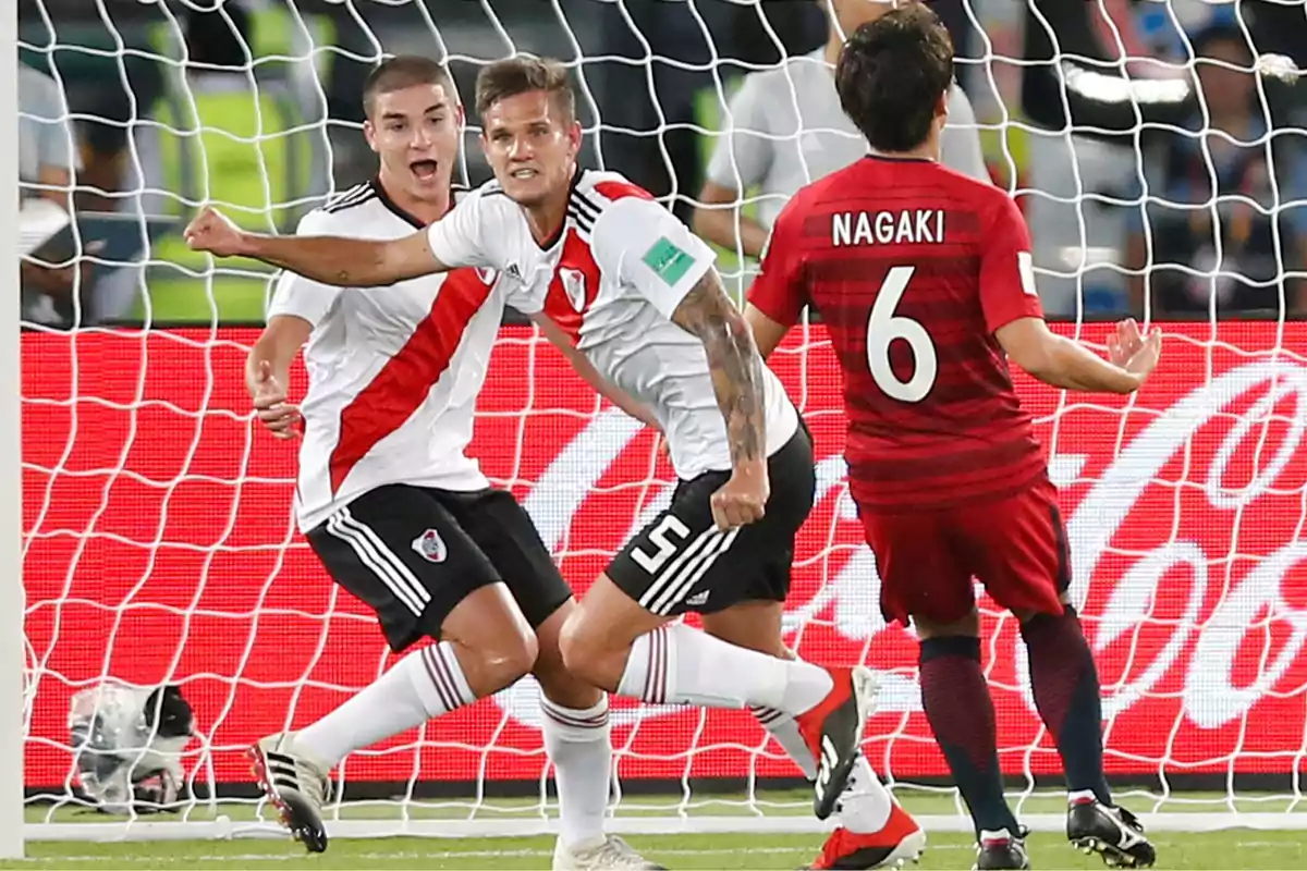 Jugadores de River Plate celebran un gol frente a un jugador del equipo rival con la red del arco de fondo Jugadores de River Plate celebran un gol frente a un jugador del equipo rival con la red del arco de fondo