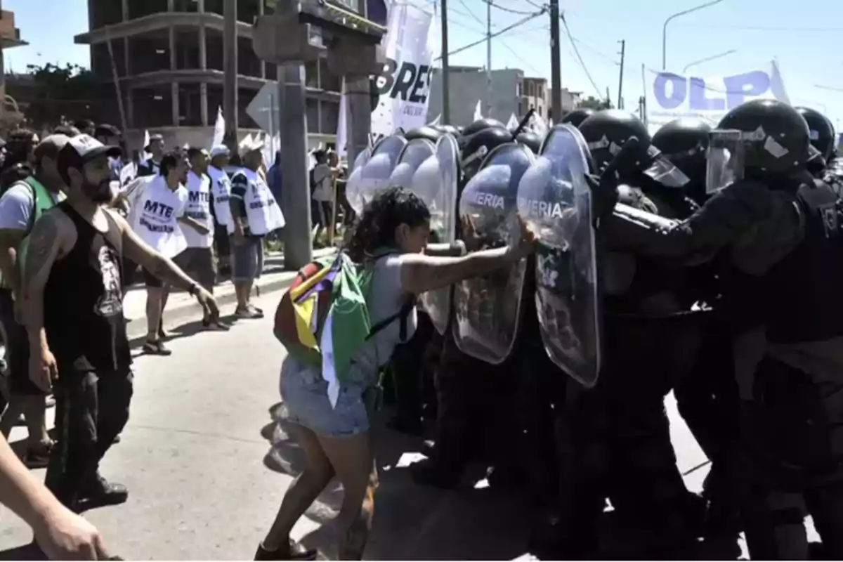 Una manifestante empuja un escudo de la policía antidisturbios durante una protesta en la calle.