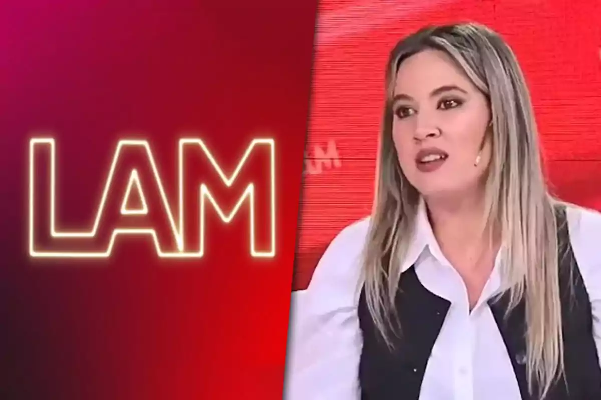 A woman with straight blonde hair, wearing a white jersey and a black vest, is sitting on a television set with a red background and the LAM logo on the left.