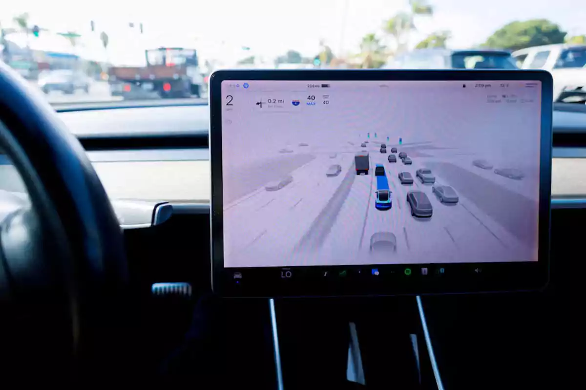 Pantalla de un coche mostrando el sistema de conducción autónoma mientras circula por una autopista con tráfico Pantalla de un coche mostrando el sistema de conducción autónoma mientras circula por una autopista con tráfico