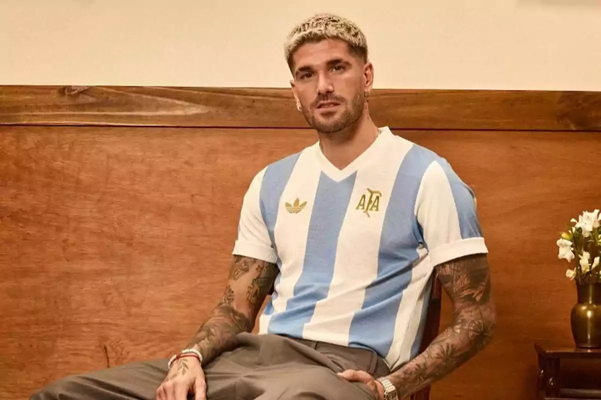 Un hombre con camiseta de fútbol de Argentina sentado en una silla de madera.