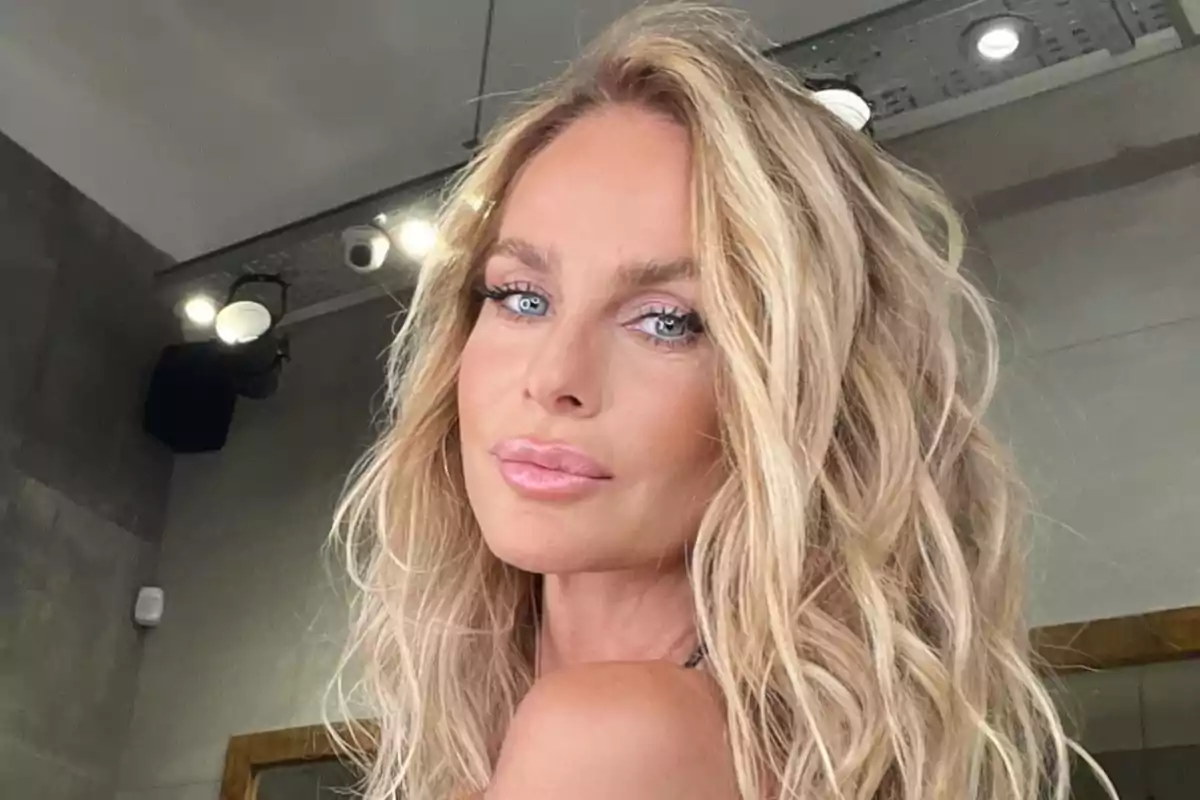 Blonde woman with wavy hair and light eyes looking at the camera in a modern indoor setting Blonde woman with wavy hair and light eyes looking at the camera in a modern indoor setting