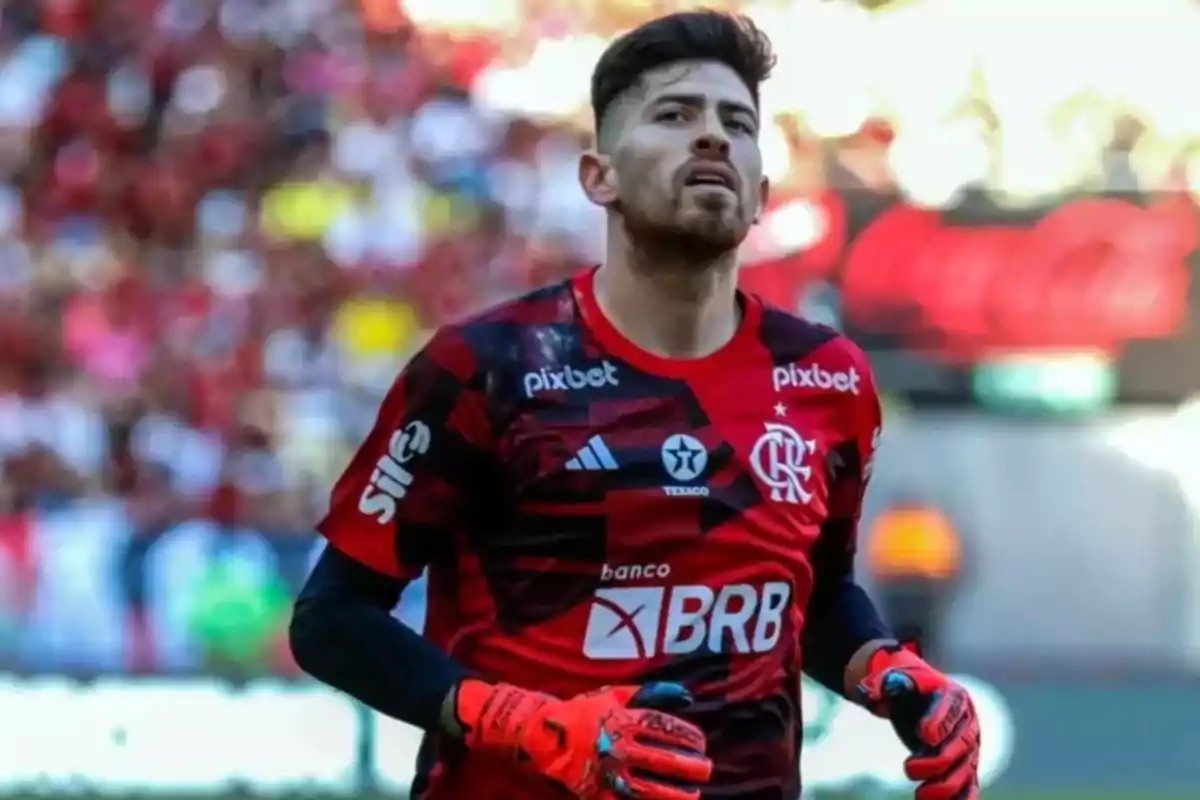 Un jugador de fútbol con uniforme rojo y negro en el campo.