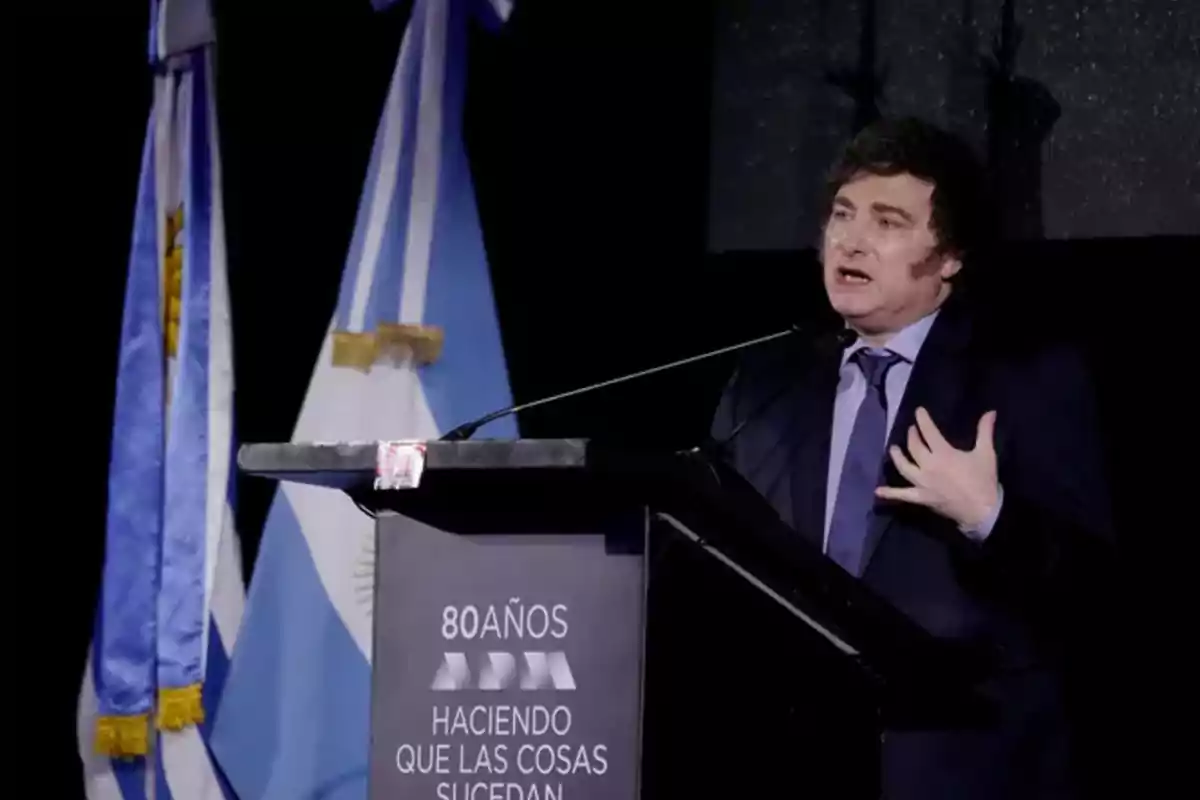Un hombre hablando en un podio con banderas argentinas de fondo. Un hombre hablando en un podio con banderas argentinas de fondo.