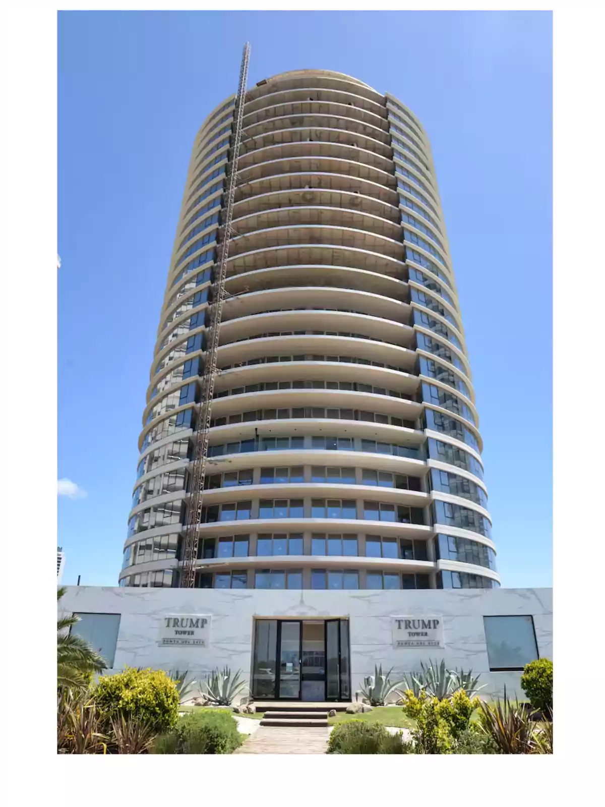 Un edificio alto y moderno con balcones curvos y una fachada de vidrio bajo un cielo azul. Un edificio alto y moderno con balcones curvos y una fachada de vidrio bajo un cielo azul.