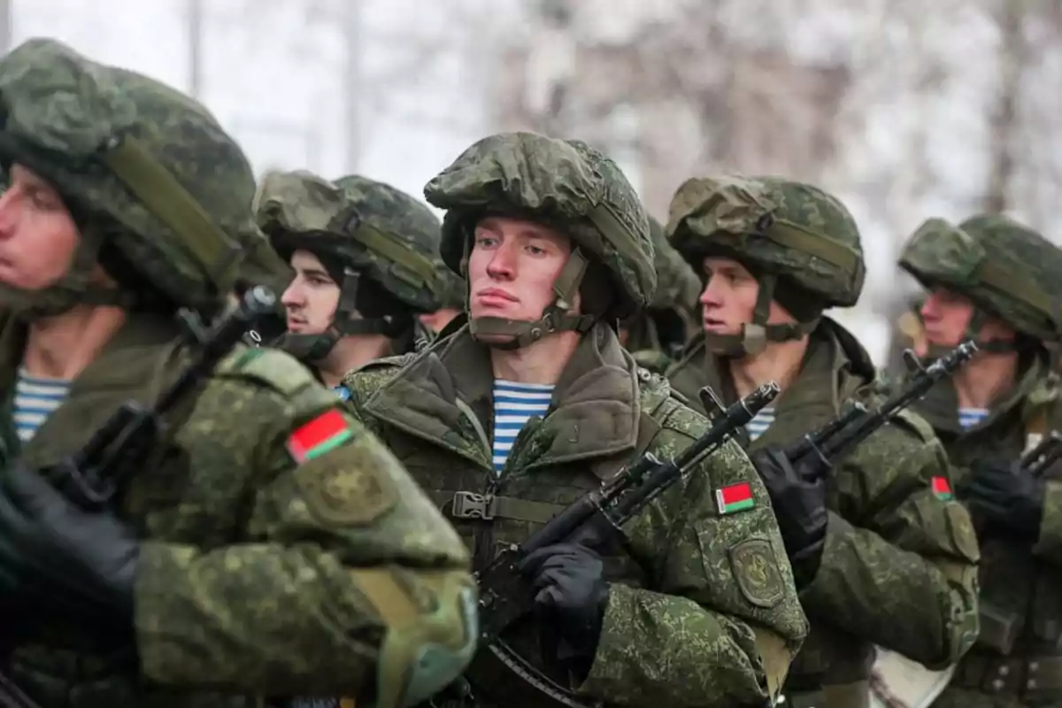 Soldados en uniforme militar verde con cascos y rifles marchando en formación. Soldados en uniforme militar verde con cascos y rifles marchando en formación.