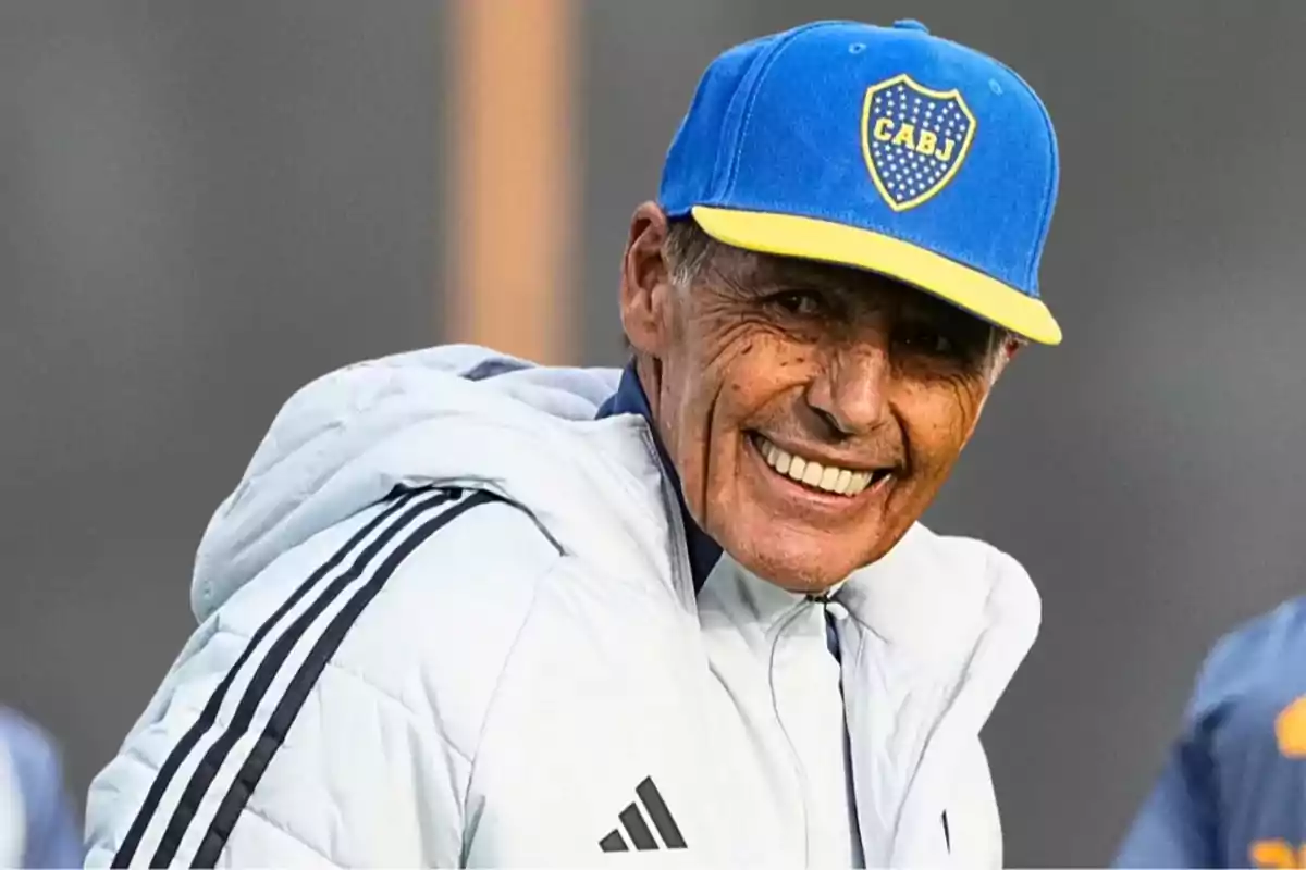 Smiling older man wearing a blue and yellow Boca Juniors cap and a white sports jacket