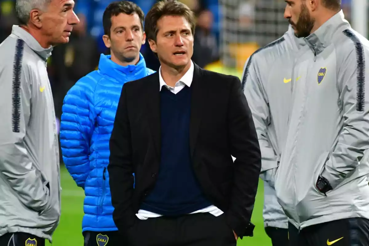 A group of men in sports and outerwear is standing on a soccer field. A group of men in sports and outerwear is standing on a soccer field.
