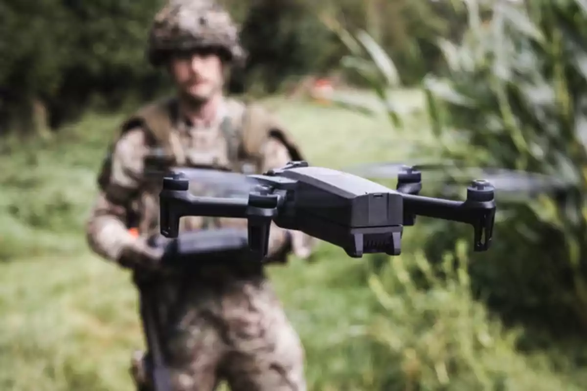 A soldier in camouflage uniform operates a black drone in a natural environment with vegetation in the background. A soldier in camouflage uniform operates a black drone in a natural environment with vegetation in the background.