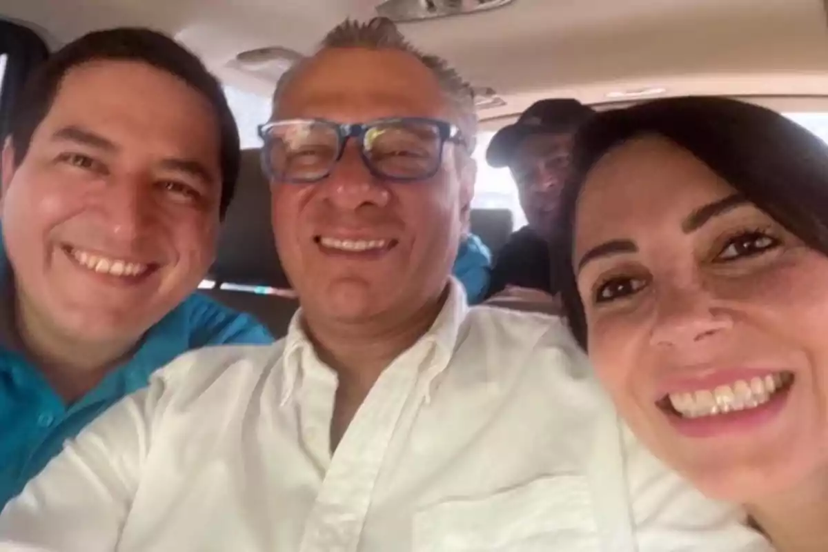 A group of people smiles while taking a selfie inside a vehicle.