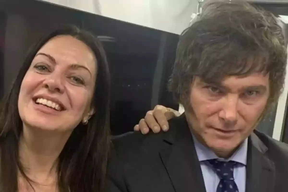 Dos personas posando para una foto, una mujer sonriente y un hombre con expresión seria, ambos con cabello oscuro.