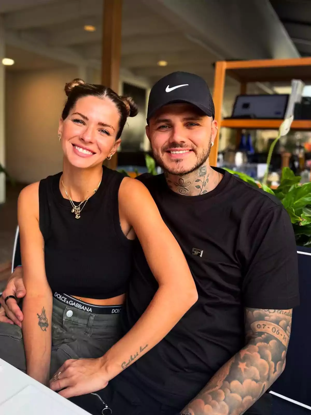 Una pareja sonriente sentada en un restaurante con plantas alrededor. Una pareja sonriente sentada en un restaurante con plantas alrededor.