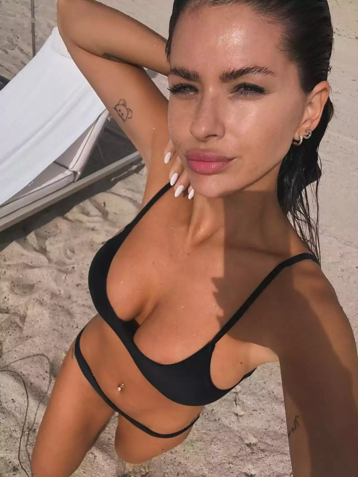 Person on the beach taking a selfie in a black bikini. Person on the beach taking a selfie in a black bikini.