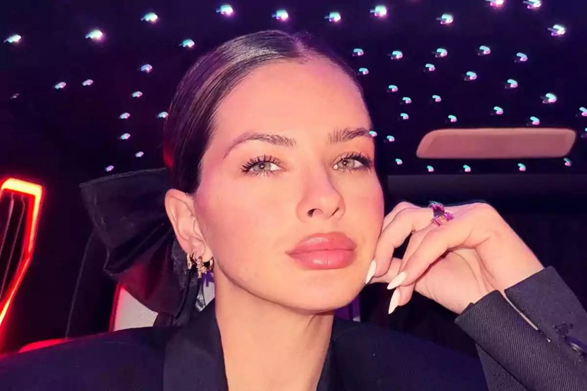 A person with their hair up and elegant makeup poses in an environment with bright lights on the ceiling.