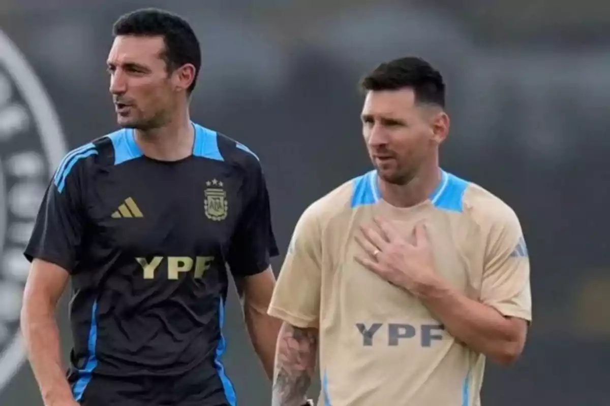 Dos hombres con ropa deportiva de la selección argentina conversan en un campo de entrenamiento