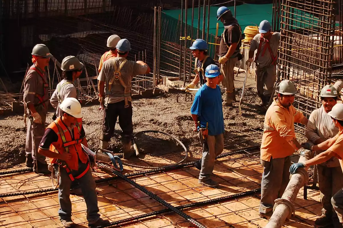 Trabajadores de la construcción con cascos y equipo de seguridad trabajando en una obra.