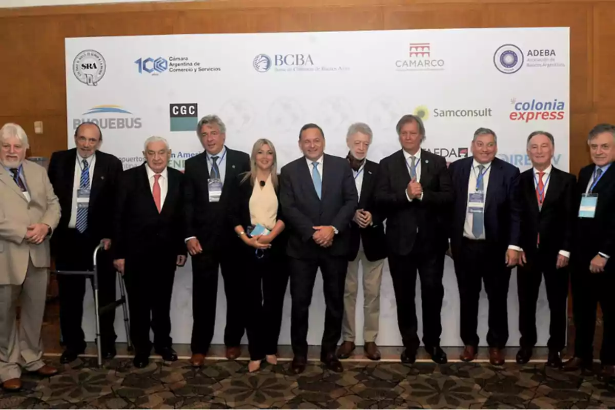 Un grupo de personas posando frente a un panel con logotipos de diversas organizaciones y empresas.