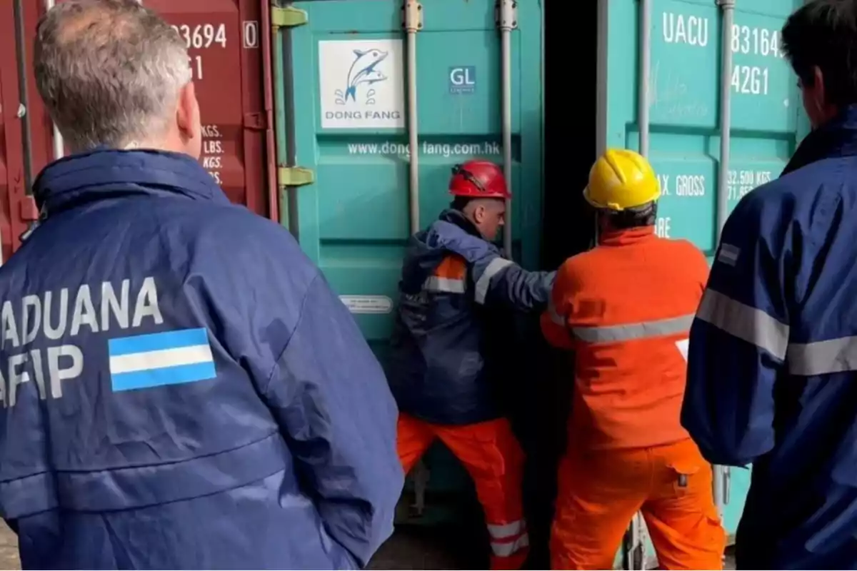 Personas de aduana y trabajadores abriendo un contenedor.