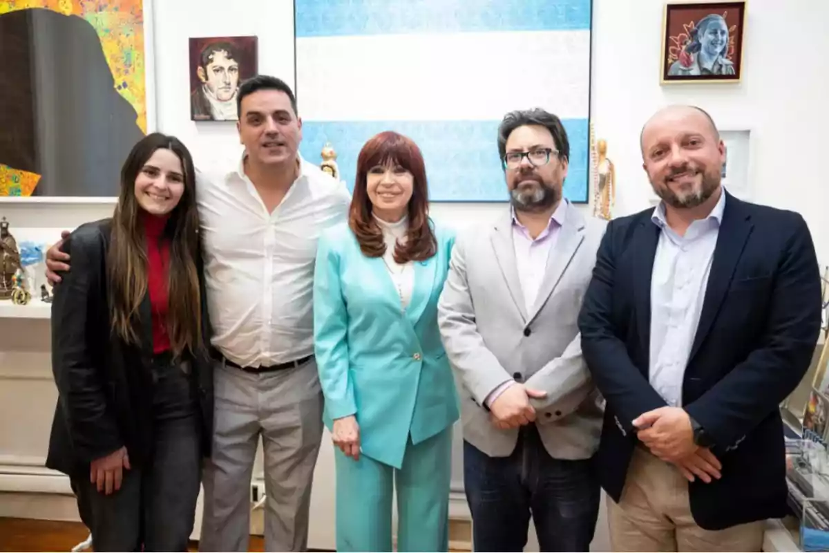 Un grupo de personas posando juntas en una sala con cuadros en la pared.