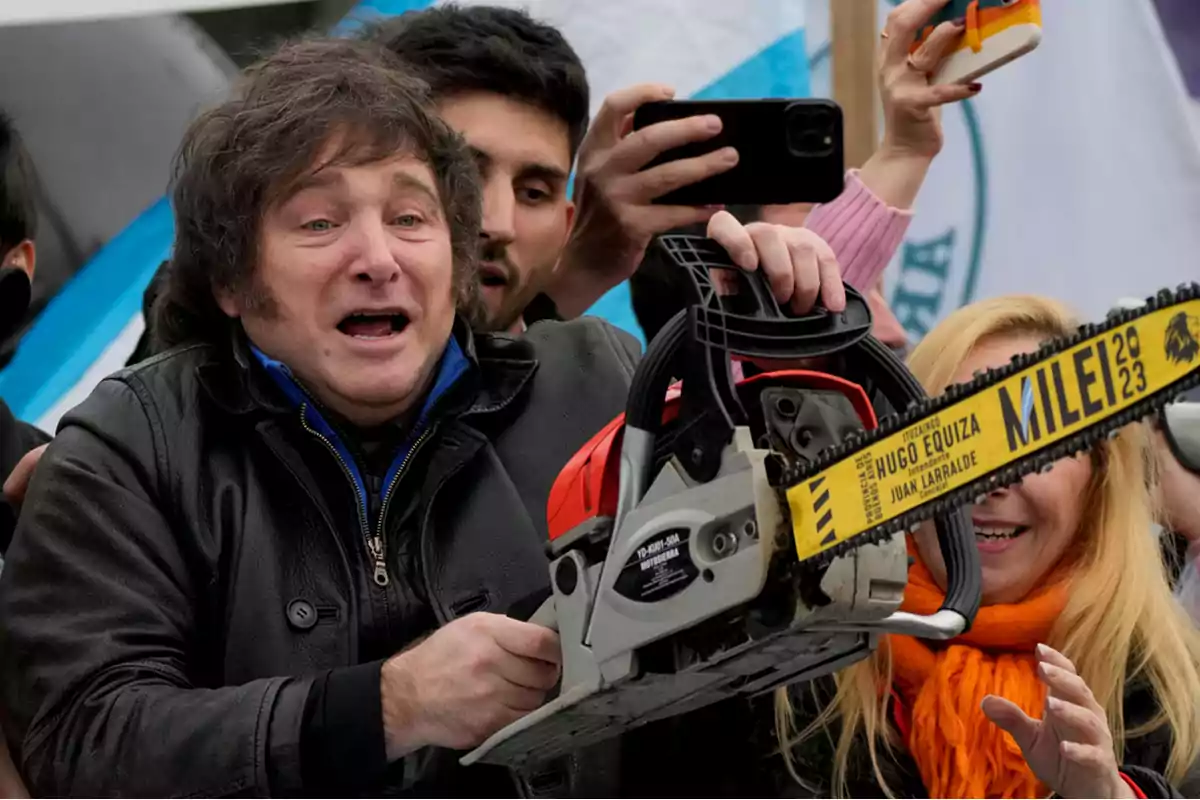 Un hombre sosteniendo una motosierra rodeado de personas que toman fotos con sus teléfonos.