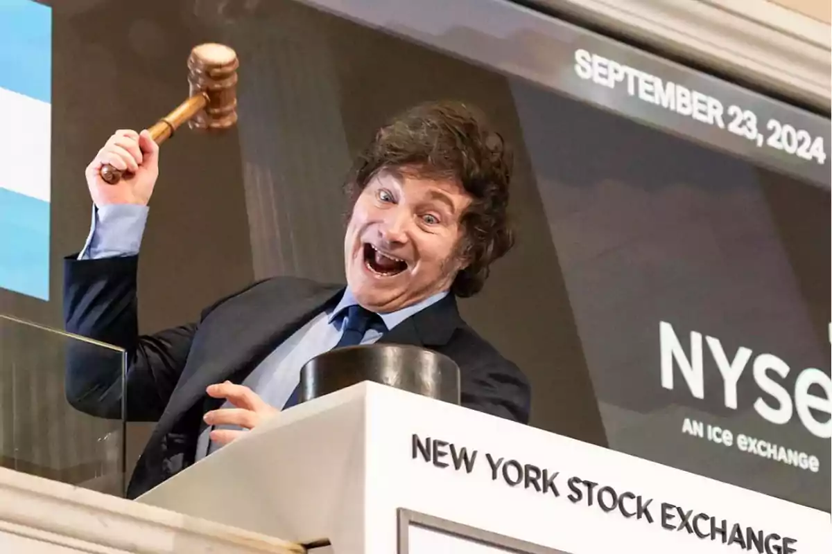 Persona sonriente levantando un mazo en el New York Stock Exchange.