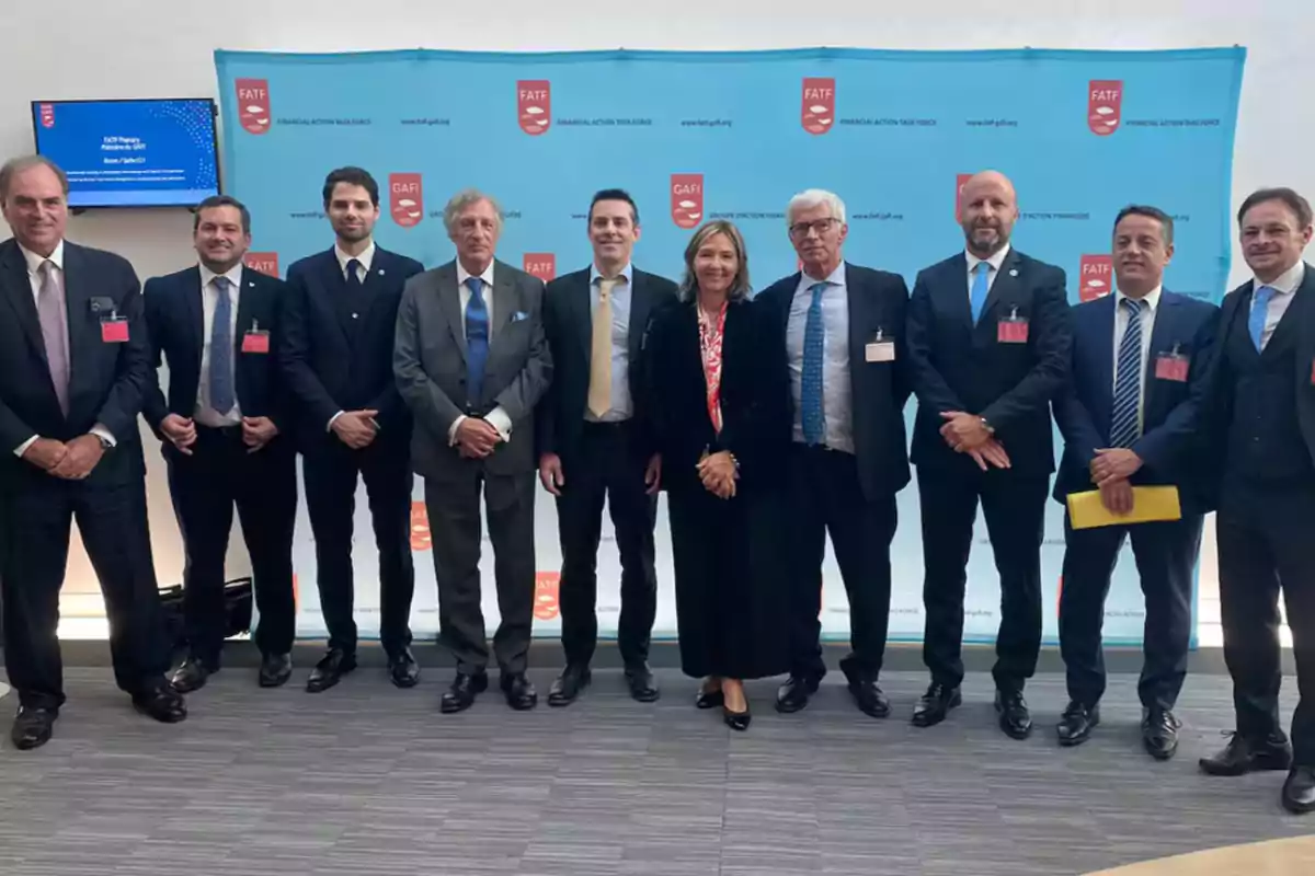 Un grupo de personas vestidas formalmente posando frente a un fondo con logotipos de FATF y GAFI.