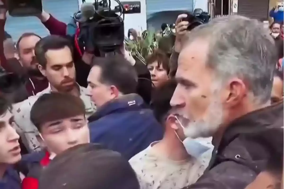 Un grupo de personas se encuentra reunido en una multitud mientras varias cámaras de televisión capturan el momento.