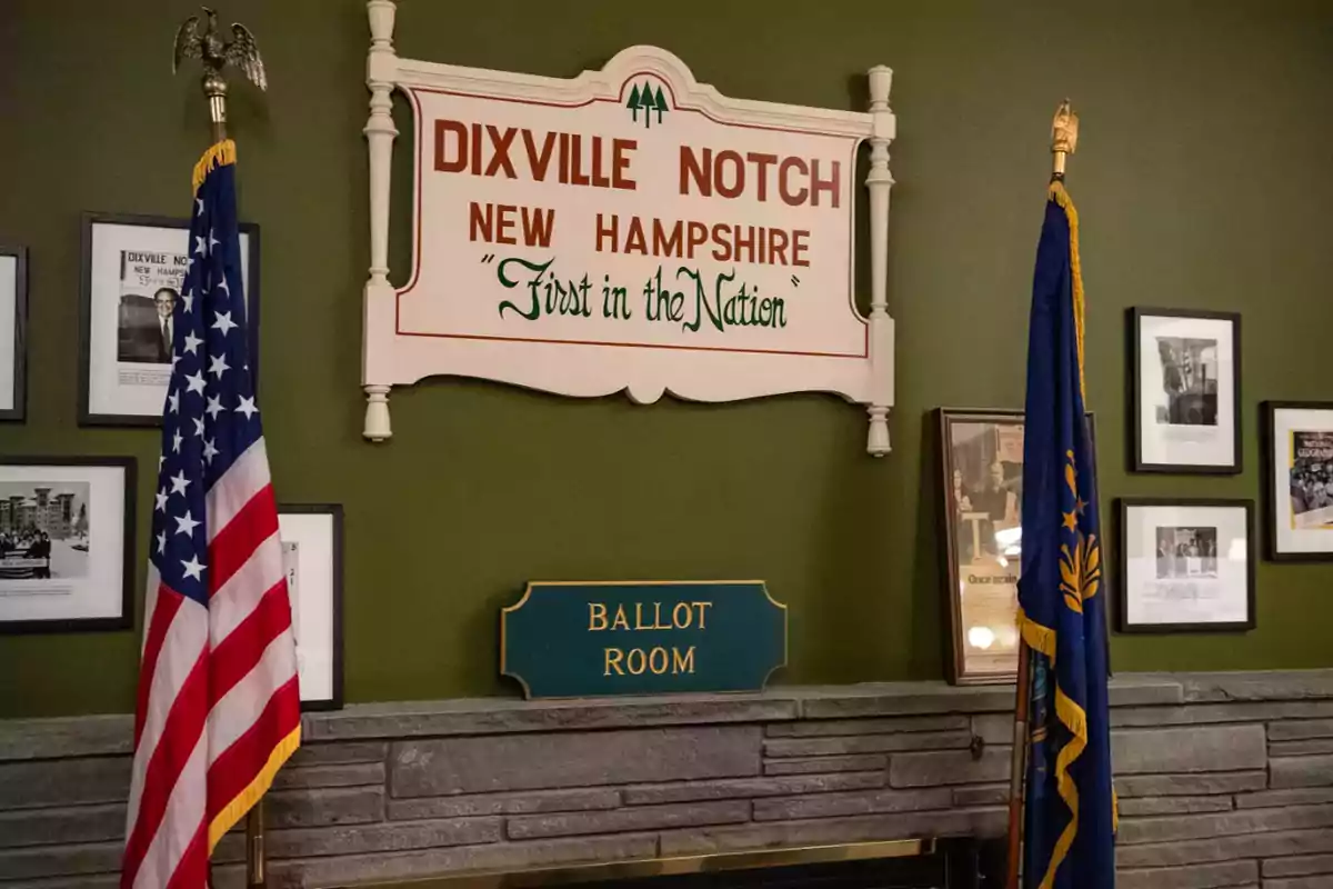 Sala de votación en Dixville Notch, New Hampshire, con banderas y un letrero que dice "First in the Nation".