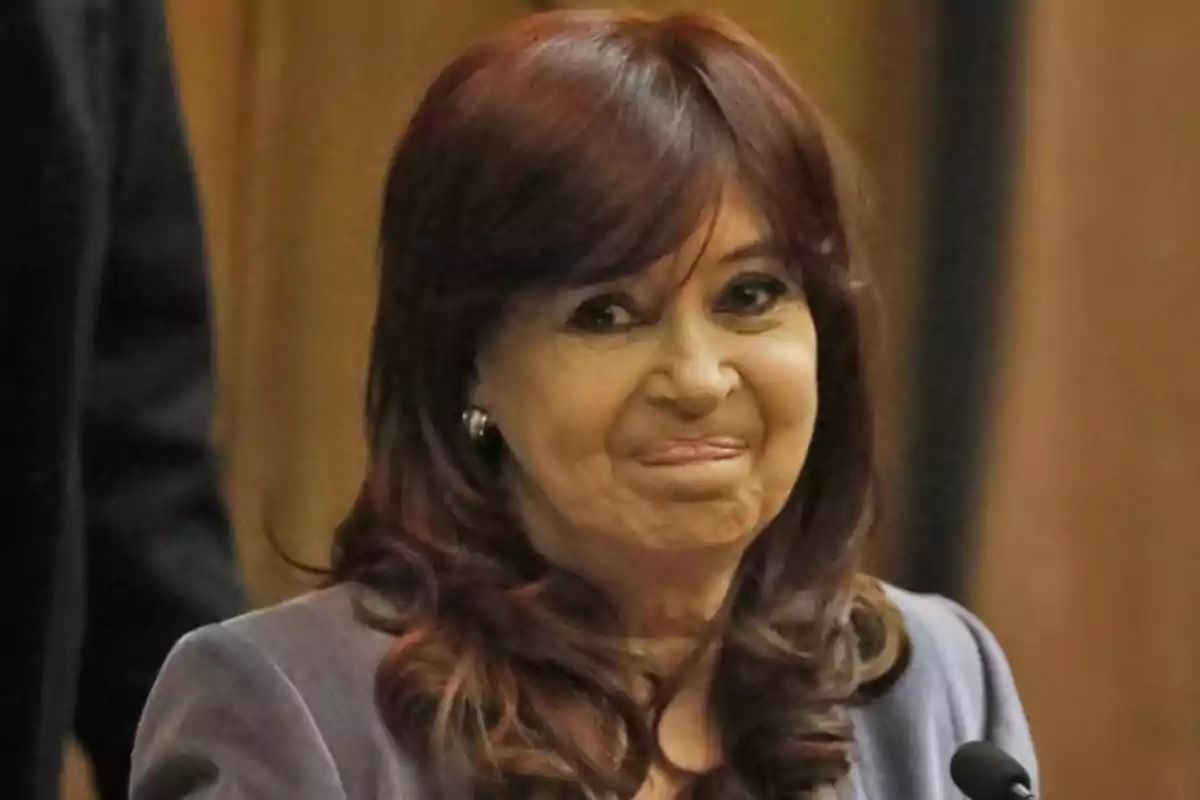 Mujer de cabello castaño oscuro y expresión sonriente en un entorno formal.