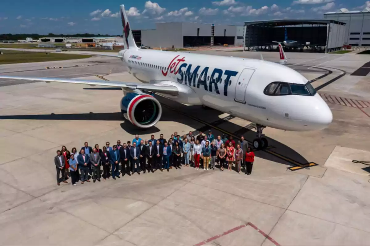 Un grupo de personas posa frente a un avión de JetSMART en un aeropuerto.