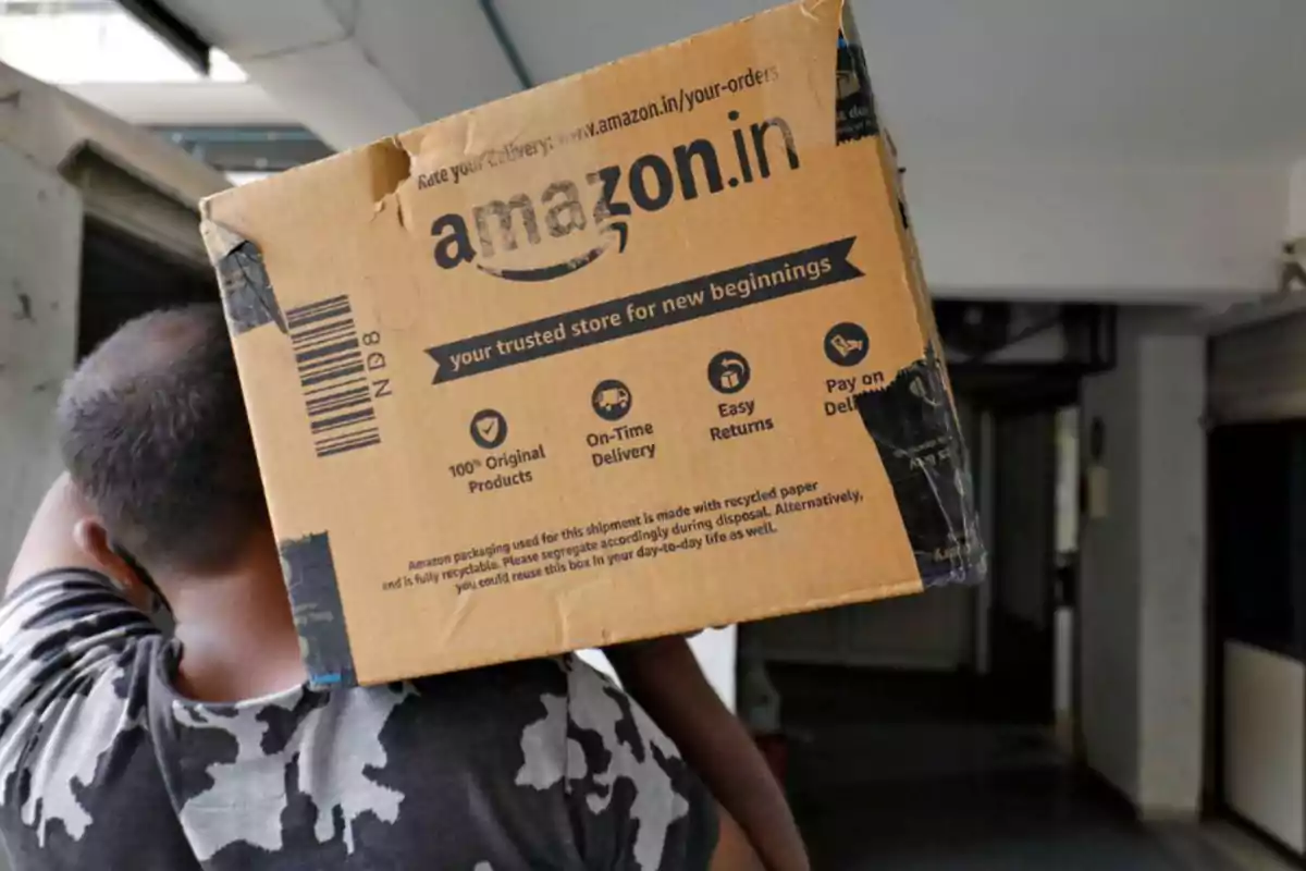 Una persona cargando una caja de Amazon en un edificio.