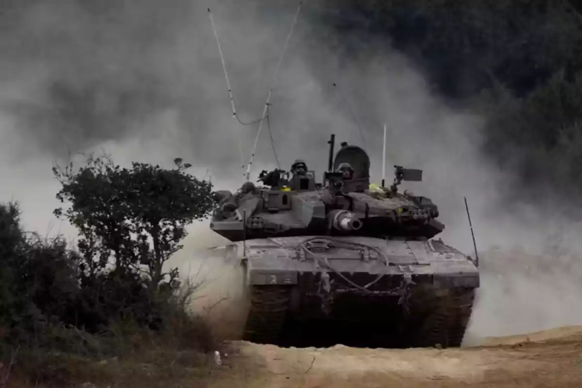 Un tanque avanzando por un camino polvoriento rodeado de vegetación.