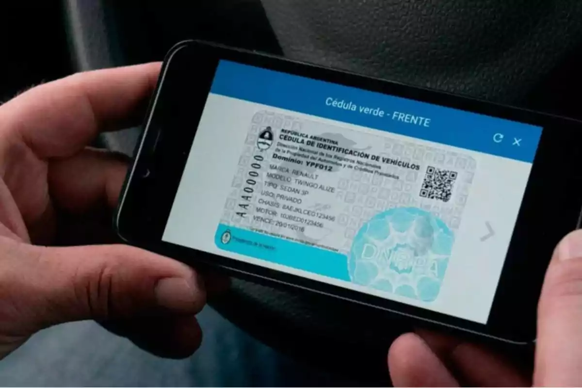 Una persona sostiene un teléfono móvil que muestra una cédula verde digital de identificación de vehículos de Argentina.