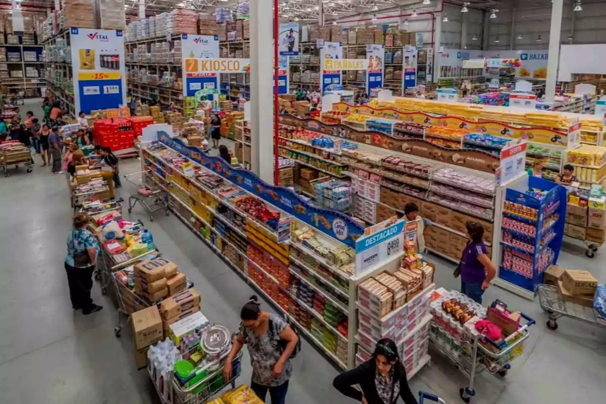 Vista de un supermercado con pasillos llenos de productos y personas comprando.