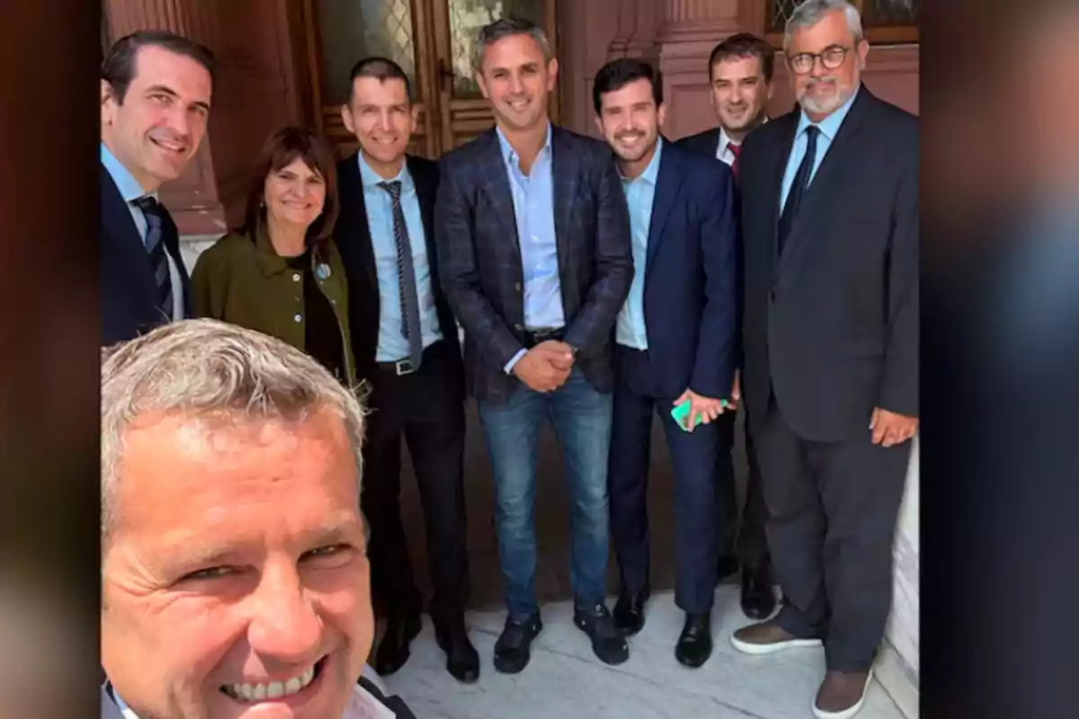 Un grupo de personas vestidas formalmente posando para una foto en un entorno arquitectónico elegante.