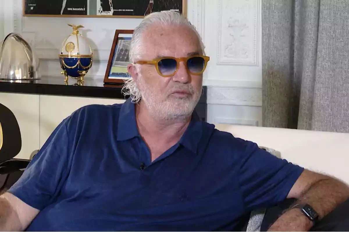Hombre con gafas de sol y camisa azul sentado en un sofá en una sala decorada. Hombre con gafas de sol y camisa azul sentado en un sofá en una sala decorada.