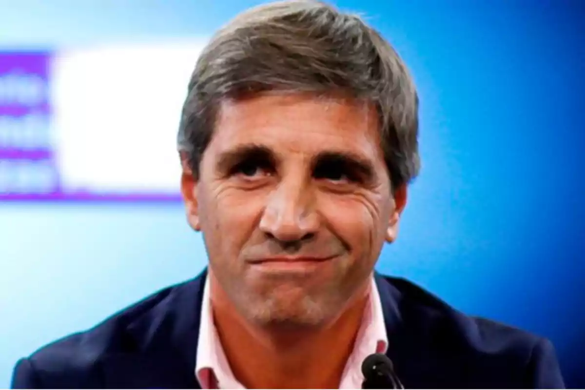 Un hombre de cabello canoso y expresión seria frente a un fondo azul.