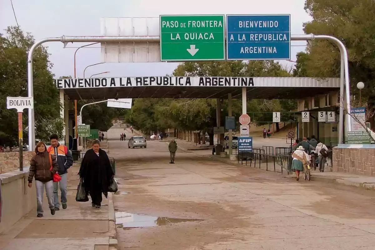 Personas caminando por un paso fronterizo entre Bolivia y Argentina, con letreros que indican la entrada a la República Argentina.