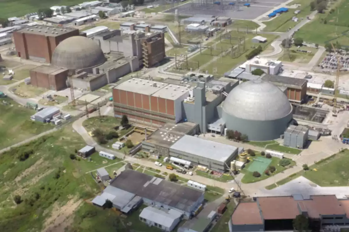 Vista aérea de una planta nuclear con edificios industriales y cúpulas grandes rodeadas de áreas verdes y caminos.