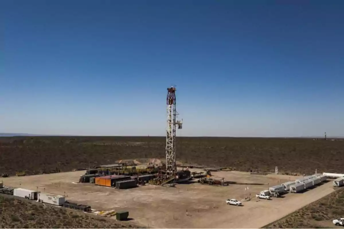 Plataforma de perforación en un campo petrolero rodeado de terreno árido bajo un cielo despejado.