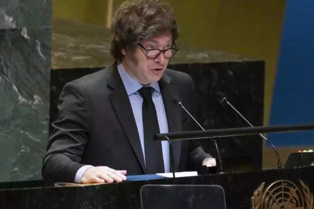 Un hombre con gafas y traje oscuro habla en un podio con el emblema de las Naciones Unidas.