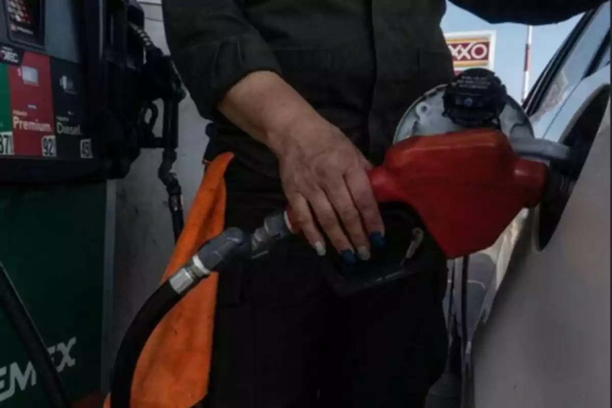 Persona llenando el tanque de un automóvil con gasolina en una estación de servicio.