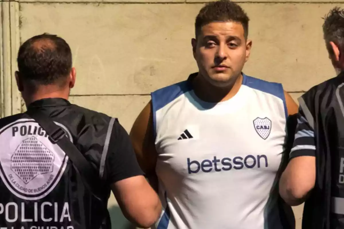 Un hombre con camiseta deportiva es escoltado por dos policías de la Ciudad de Buenos Aires.