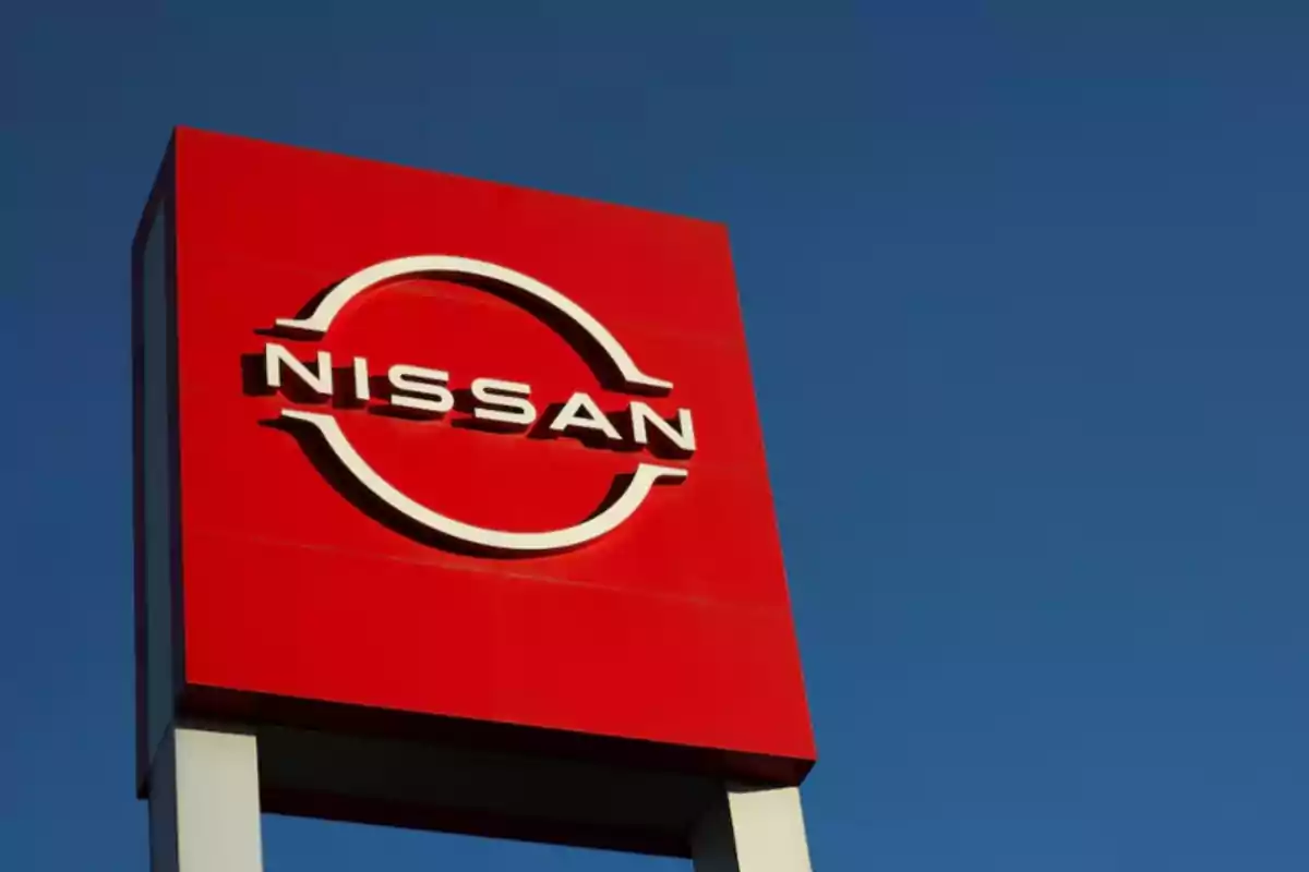 Un letrero rojo de Nissan con el logotipo en blanco sobre un fondo de cielo azul.