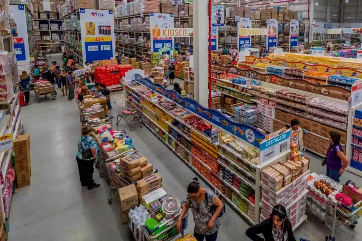 People shopping in a wholesale supermarket with shelves full of products and shopping carts.