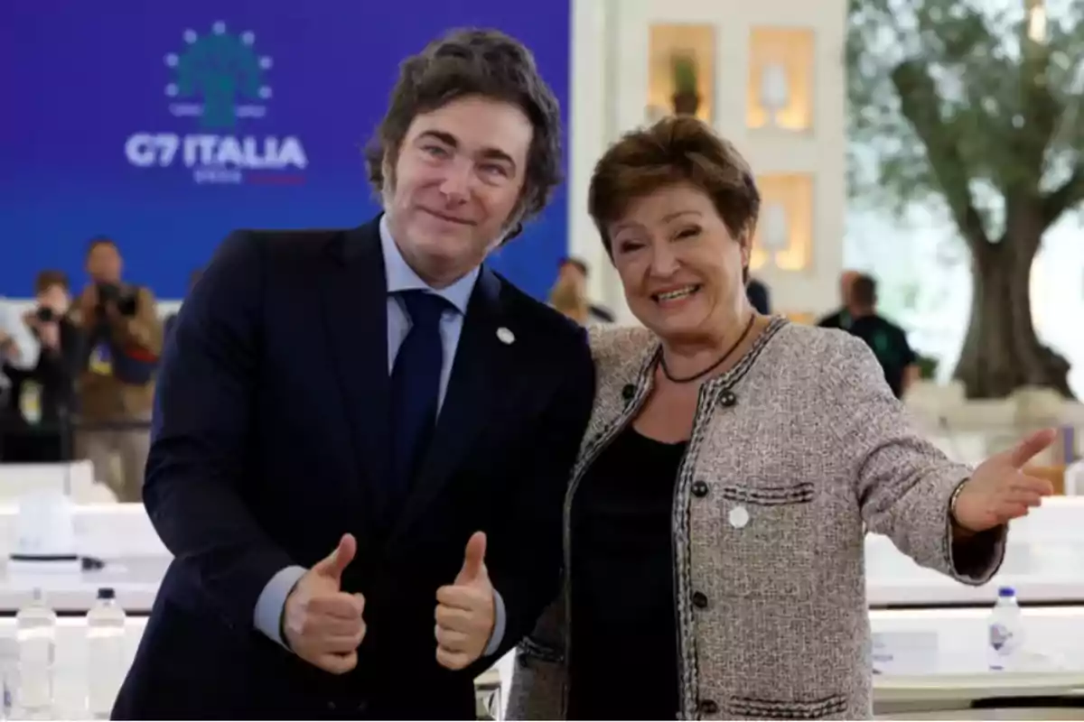 Dos personas posan sonriendo en un evento del G7 en Italia, una de ellas hace un gesto de aprobación con los pulgares hacia arriba.