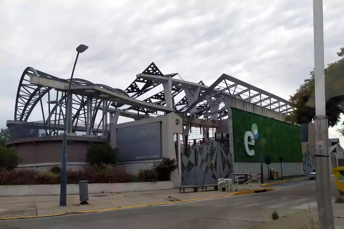 Edificio moderno con estructura metálica y fachada verde en un entorno urbano.